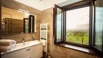 A modern bathroom with a large window, a white sink, and a towel rack.