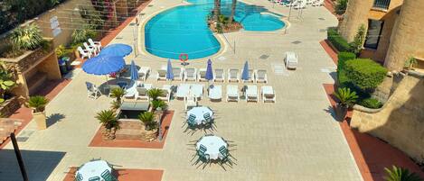 Piscine extérieure en saison, parasols, chaises longues
