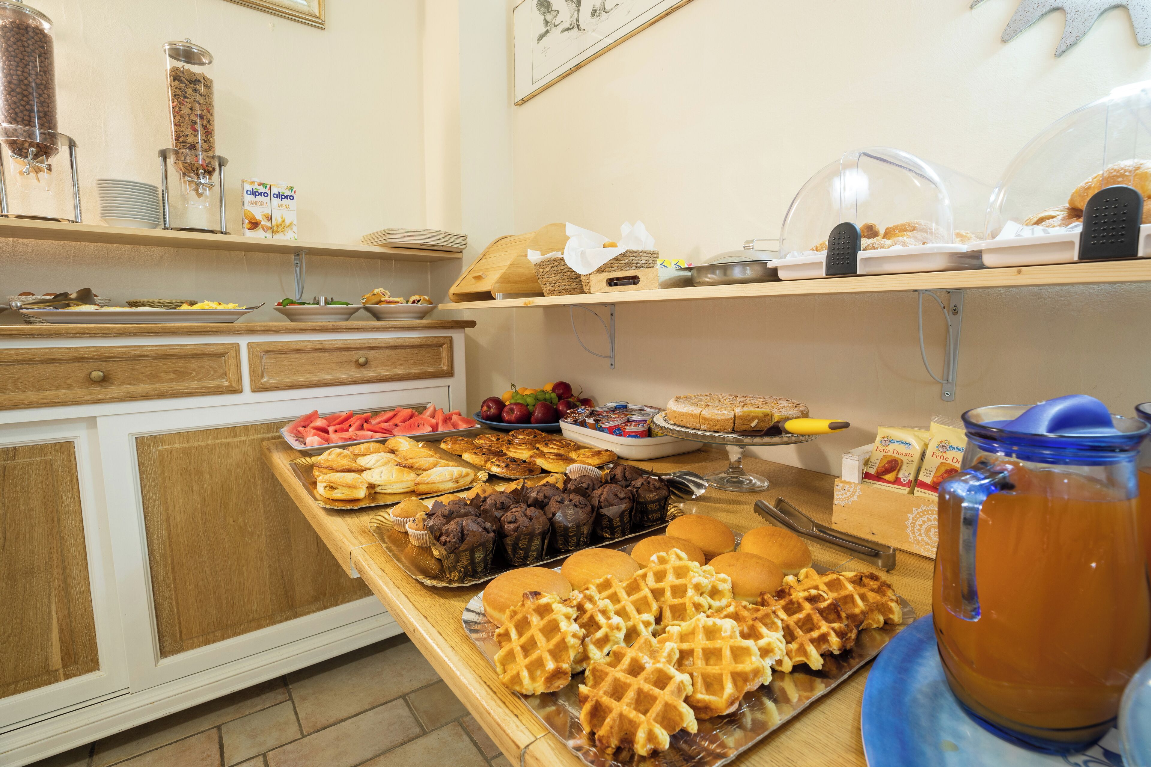 A buffet with various food items including waffles, pastries, and fruits.