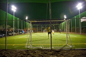 Un campo deportivo con un arco y una red, rodeado por una valla.