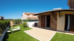 A house with a patio, a lawn, and a stone wall. - Hotel Daniel (Olbia)