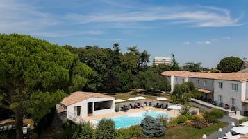 Relax by the serene outdoor pool surrounded by lush greenery and mature trees.