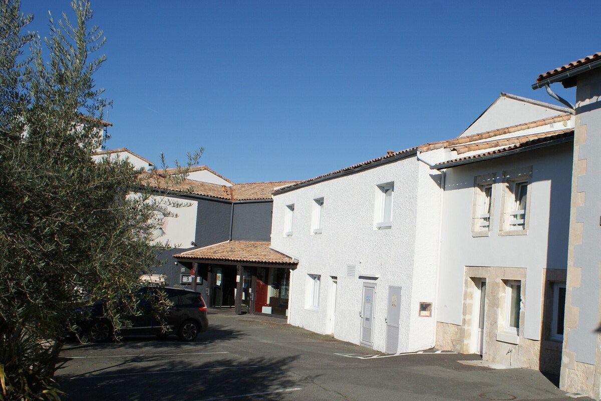 A building with a white facade, multiple windows, and a tiled roof.