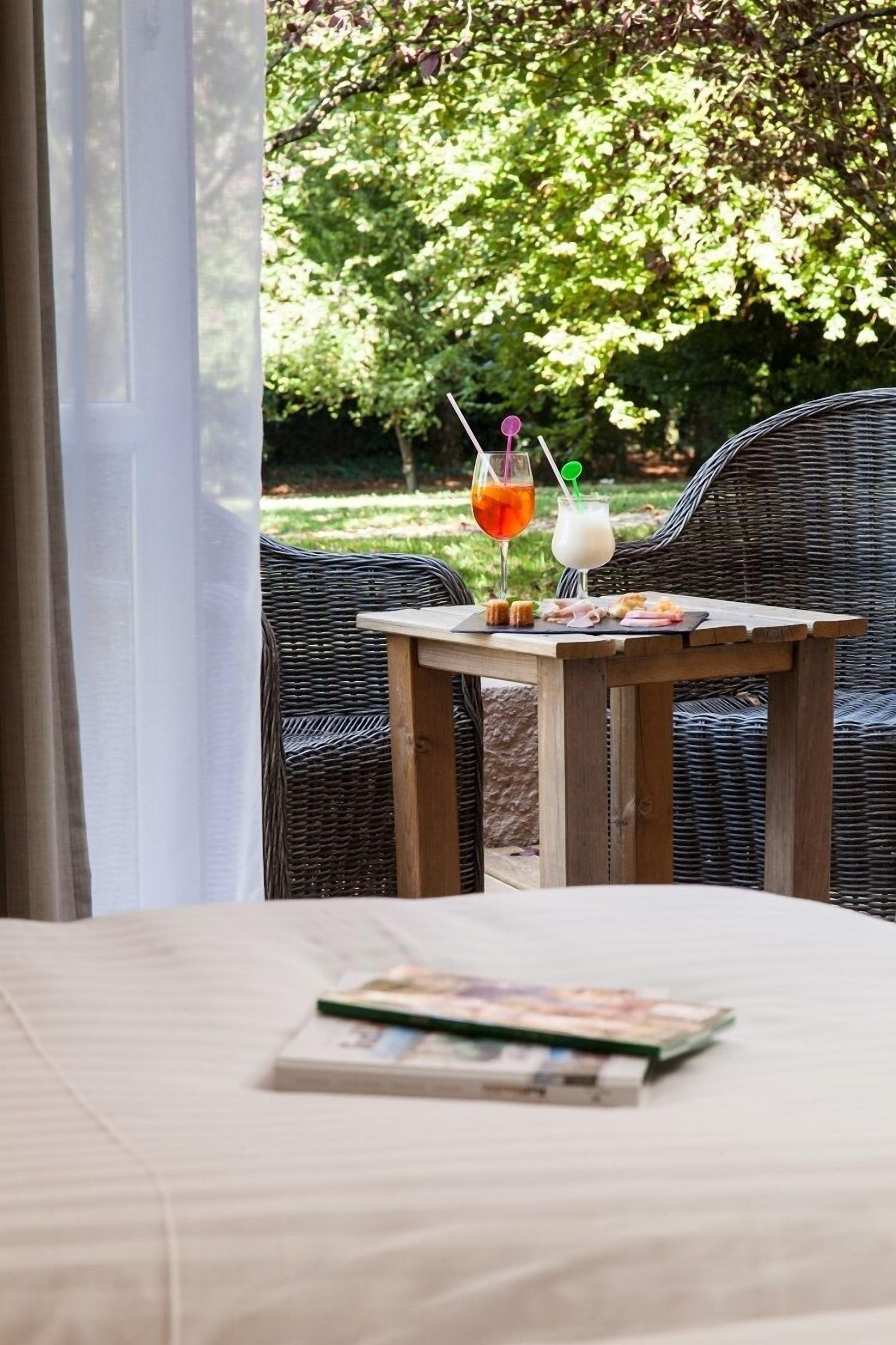 A wicker chair and a small wooden table with a drink and snacks.