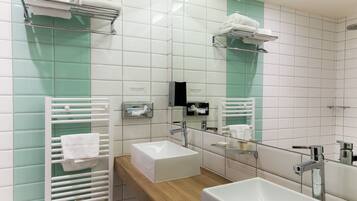 A modern bathroom with a large mirror, two sinks, a towel rack, and a heated towel rail.