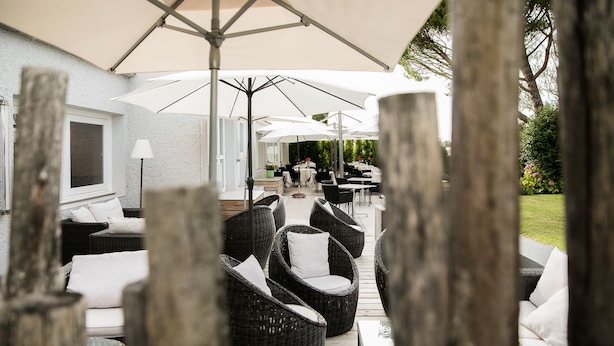 An outdoor patio area with wicker furniture and umbrellas, surrounded by a wooden fence. - LOGIS HOTEL LE RABELAIS (Fontenay-le-Comte)