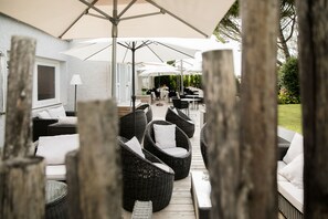 An outdoor patio area with wicker furniture and umbrellas, surrounded by a wooden fence.