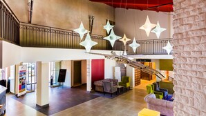 A spacious lobby with a high ceiling, a staircase, and hanging star-shaped lights. - LOGIS HOTEL LE RABELAIS (Fontenay-le-Comte)