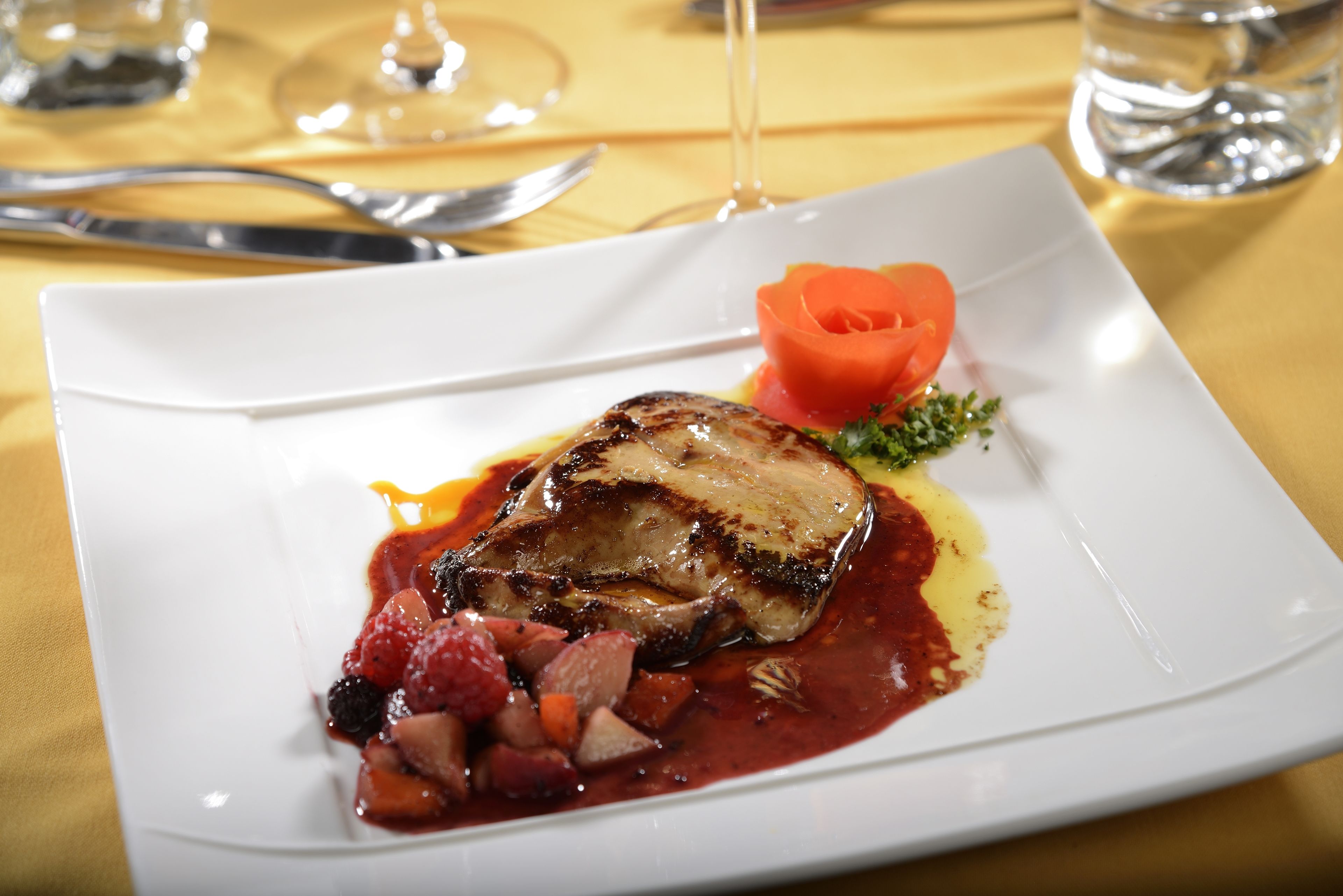 Un plato blanco con carne, verduras y salsa.