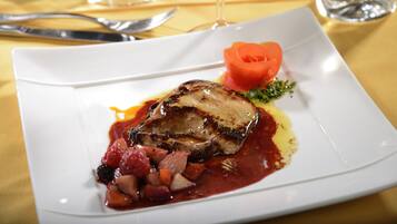Un plato blanco con carne, verduras y salsa.