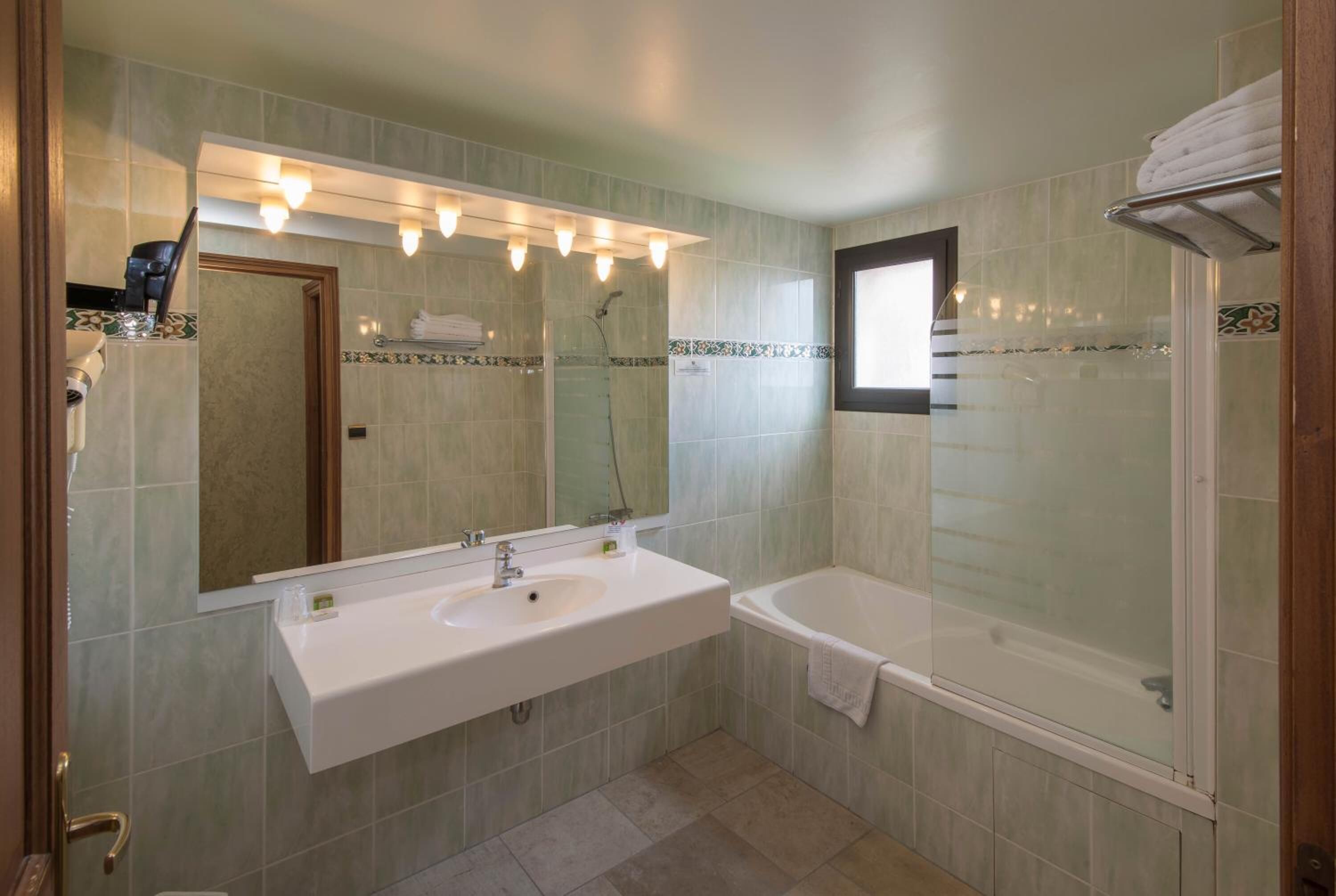 Un baño con lavamanos, espejo y bañera.