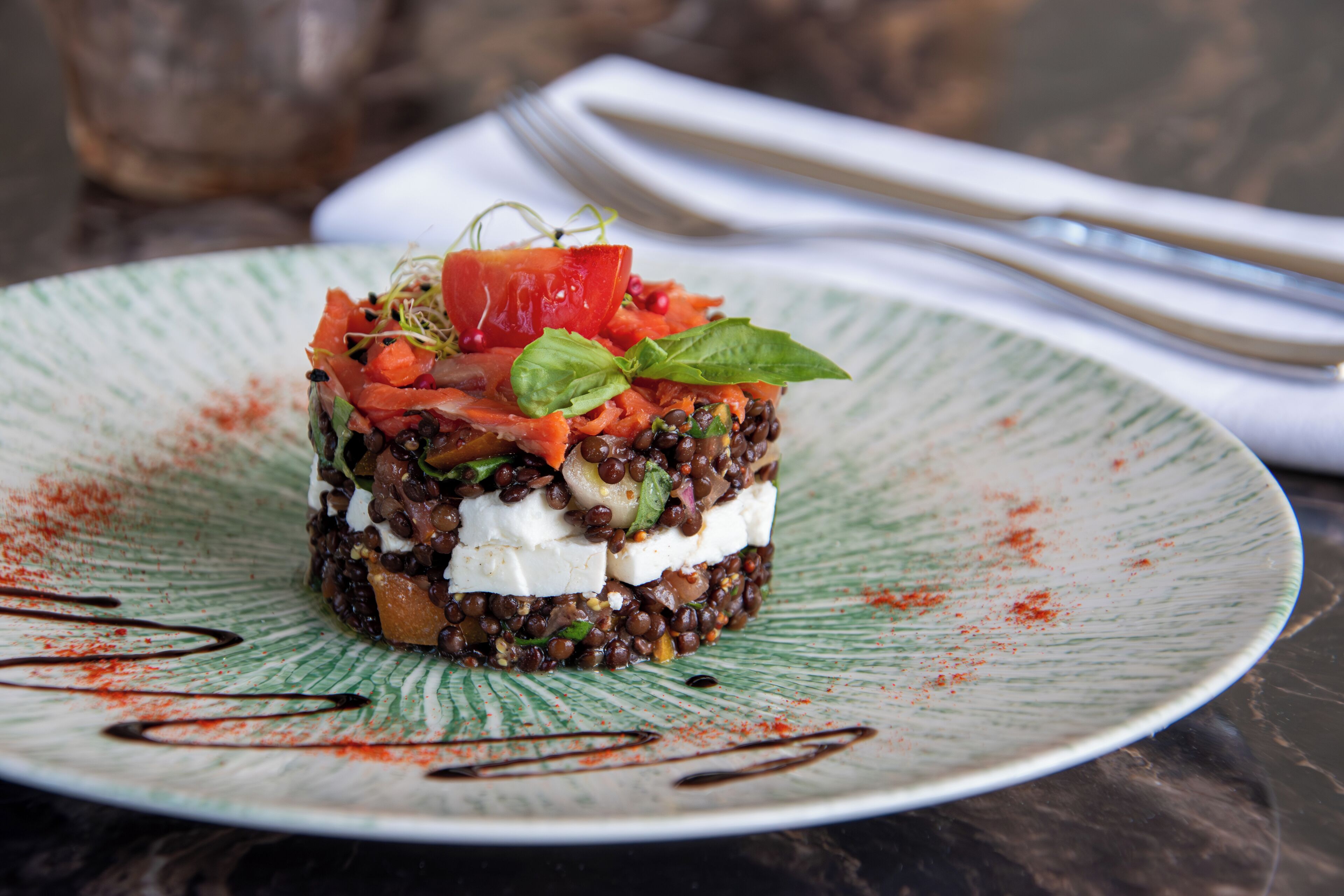 A plated dish with layers of ingredients and a drizzle of sauce.