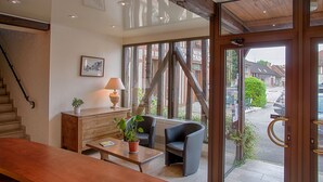 Un cuarto amplio con una escalera de madera, una mesa de centro de madera con una planta en maceta, una lámpara y un sillón cómodo.