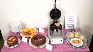 En buffet med forskellige desserter og en vaffelmaskine.