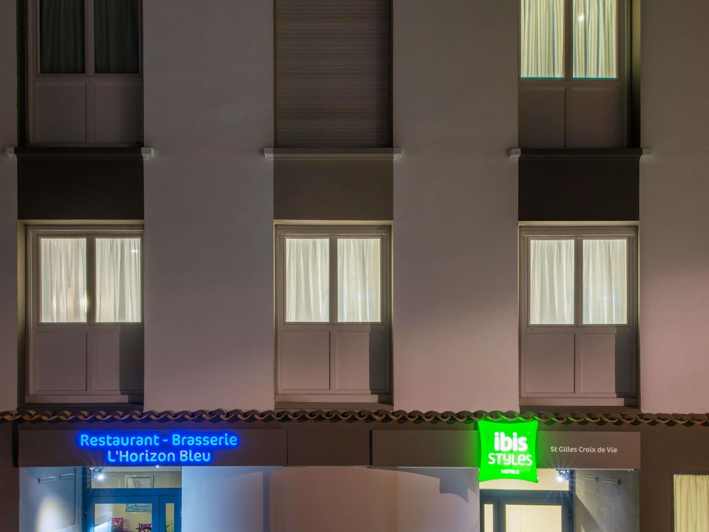 A building with multiple windows, a restaurant sign, and a hotel sign.