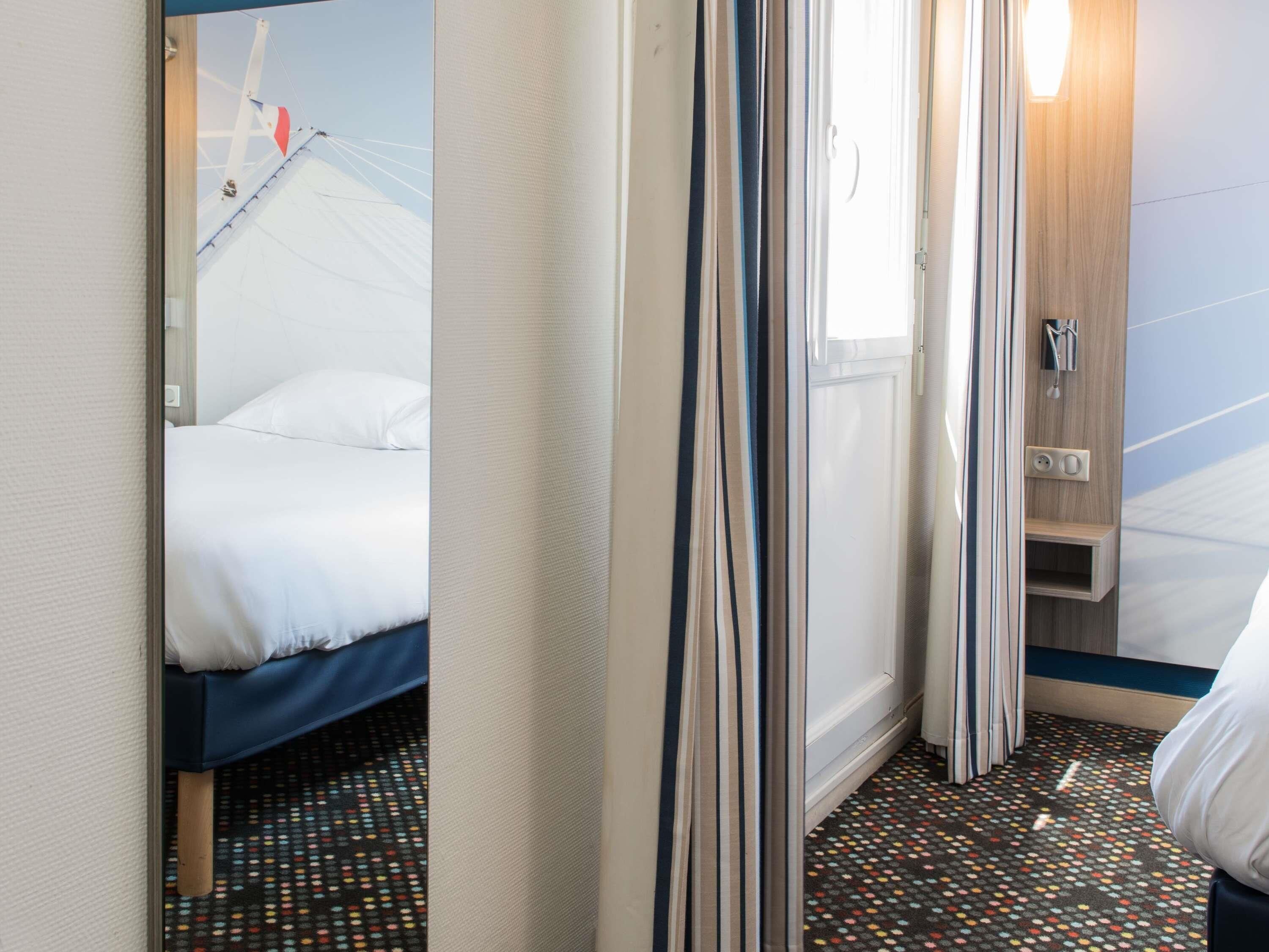 A hotel room with a bed, a shower area, and a window.