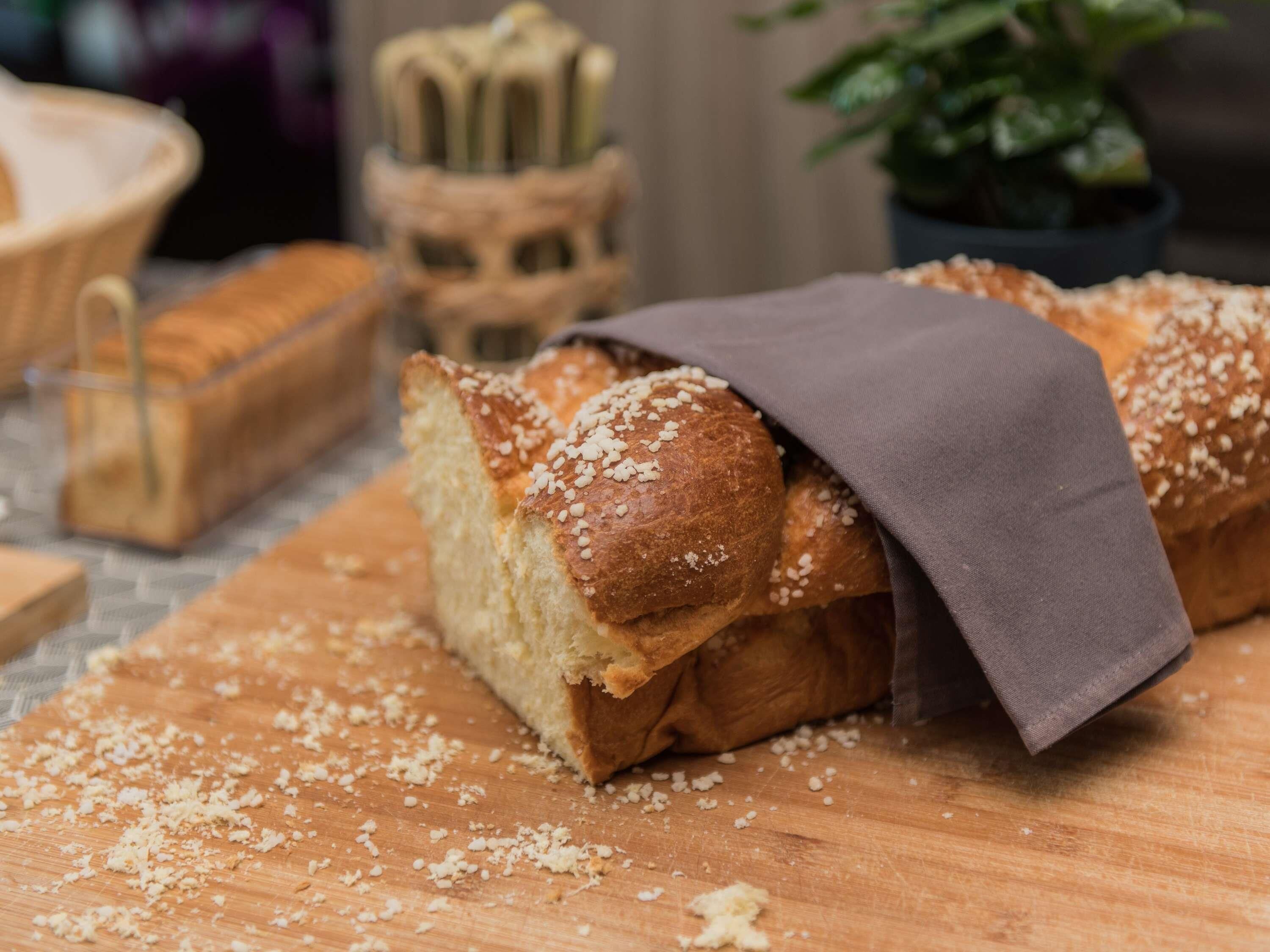 Een brood met een doek erop, op een houten oppervlak met kruimels.