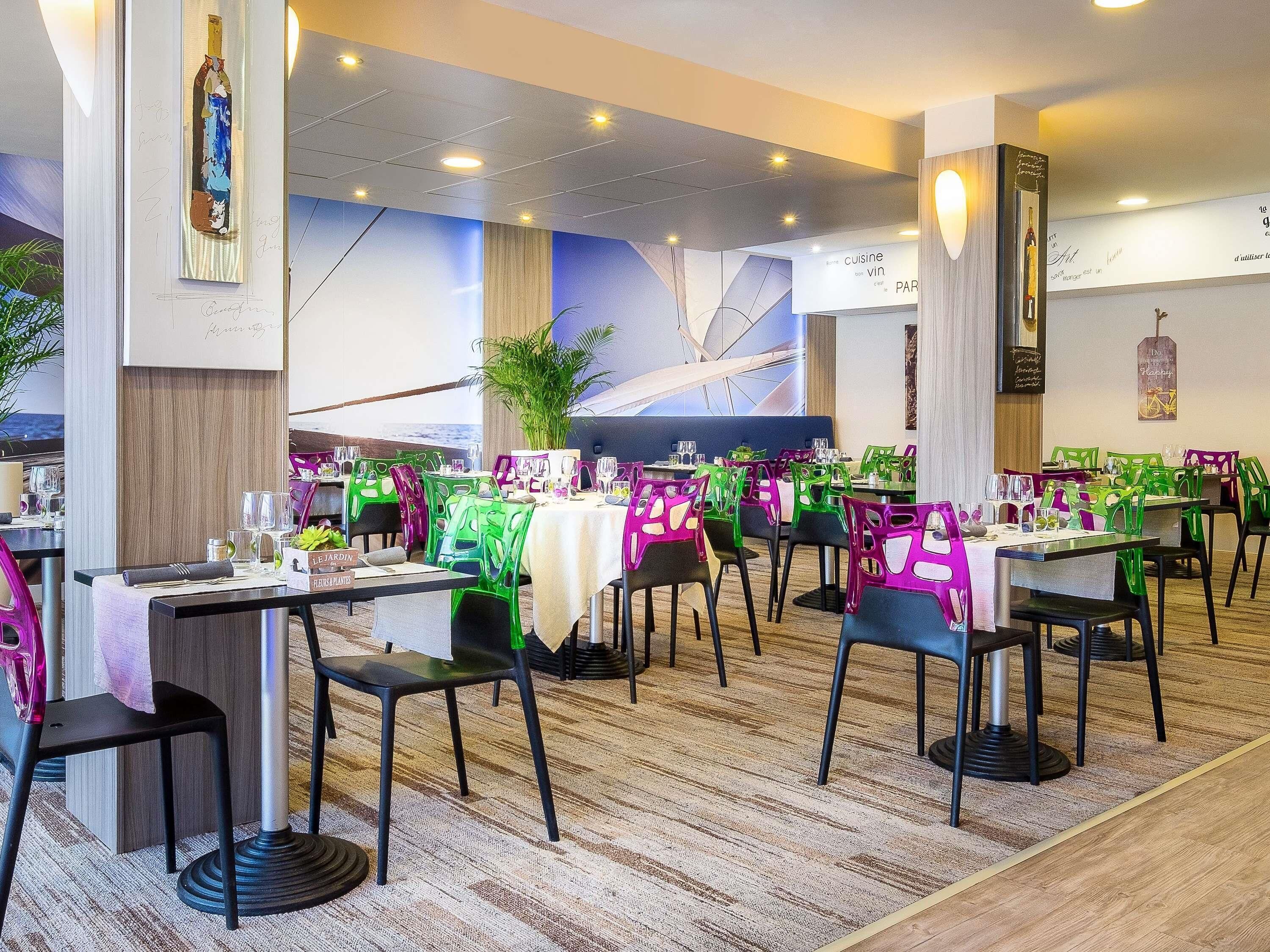 A restaurant with tables set for dining, chairs, and a large plant in the center.