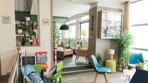 A modern hotel lobby with a seating area, a reception desk, and a large window. - ibis Styles Saint Gilles Croix de Vie (Saint-Gilles-Croix-de-Vie)