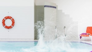 A swimming pool with a water fountain, a lifebuoy, and two orange lounge chairs. - ibis Styles Saint Gilles Croix de Vie (Saint-Gilles-Croix-de-Vie)