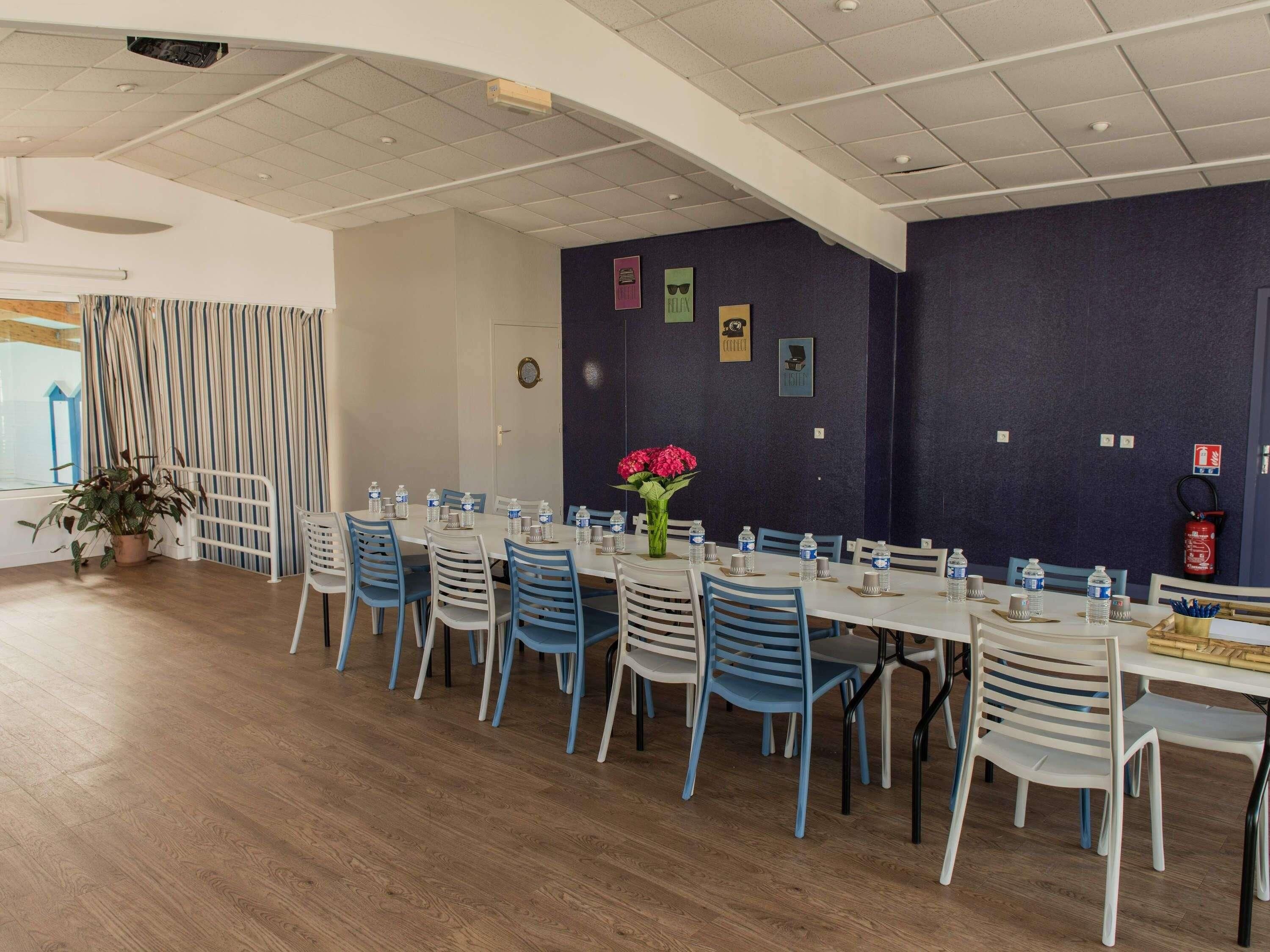 A dining area with tables and chairs, a potted plant, and a fire extinguisher on the wall.