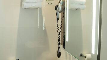 Un baño moderno con un lavamanos blanco, inodoro y cabina de ducha con mampara de vidrio.