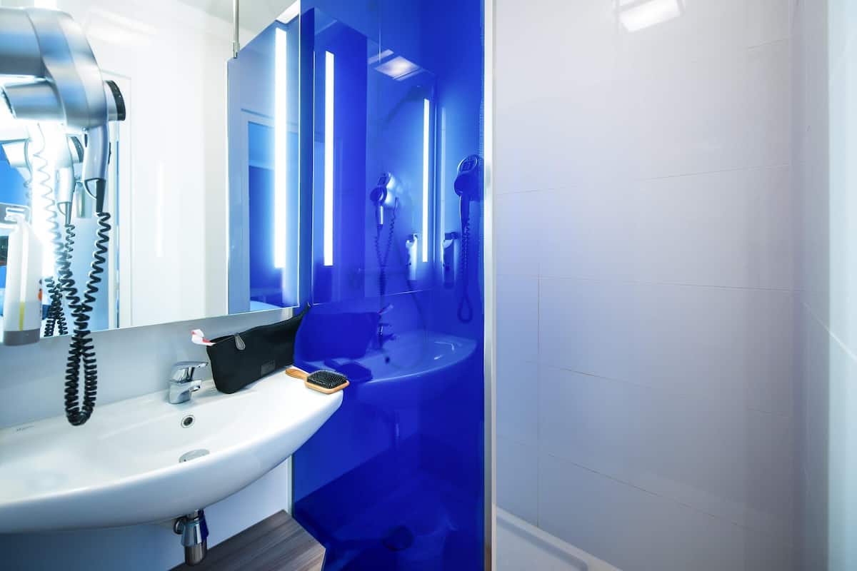 A modern bathroom with a white sink, a hairdryer, and a mirror.