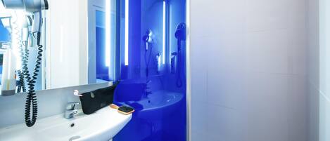 A modern bathroom with a white sink, a hairdryer, and a mirror.