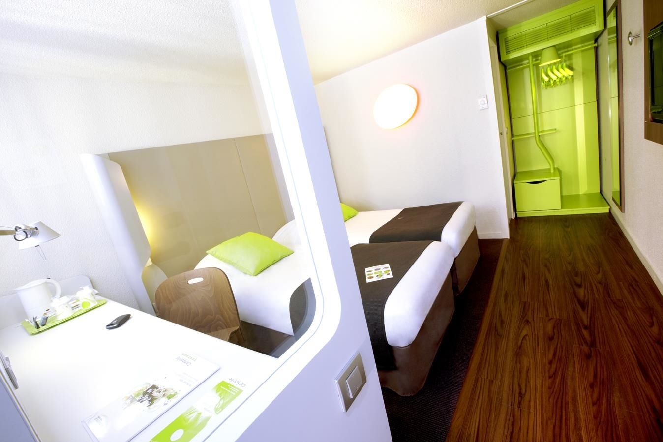 Habitación de hotel pequeña con cama, mesita de noche y un rincón de descanso.