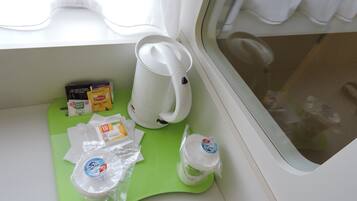 Een kitchenette met een koffiezetapparaat, theezakjes en een groene dienblad.