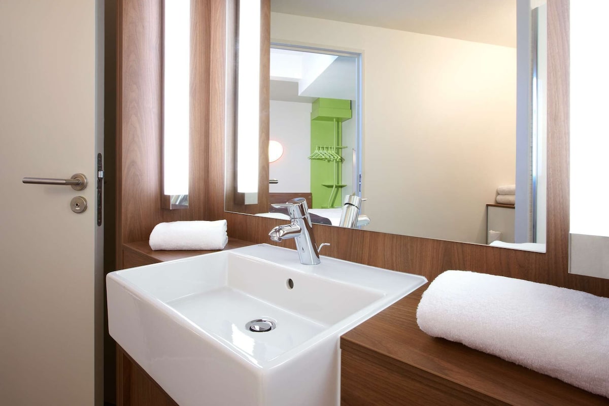 A modern bathroom with a white sink, a mirror, and a towel.