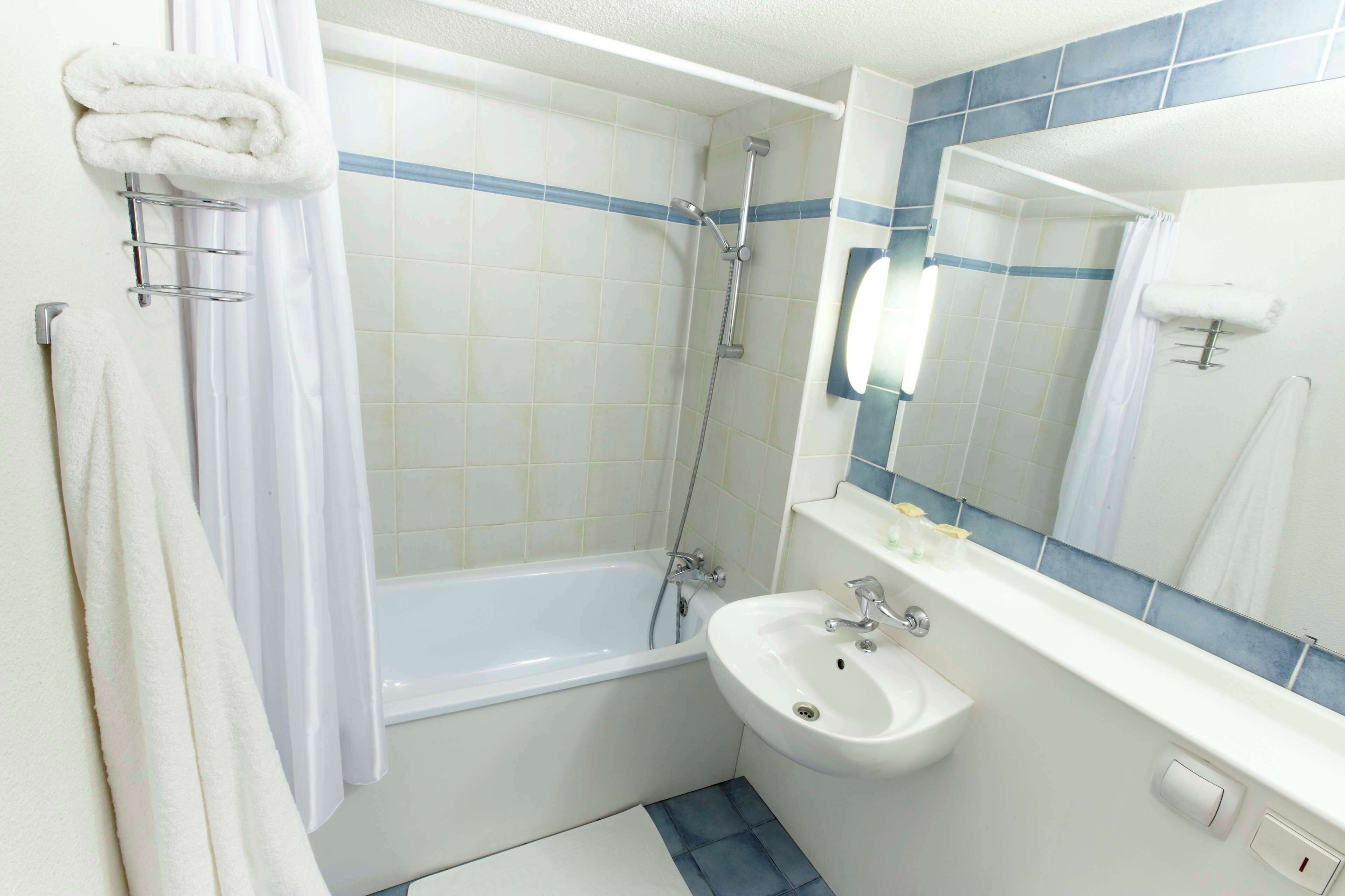 A bathroom with a bathtub, a sink, and a mirror.