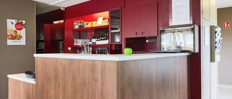 Una cocina moderna con una isla de madera, armarios rojos y un refrigerador.