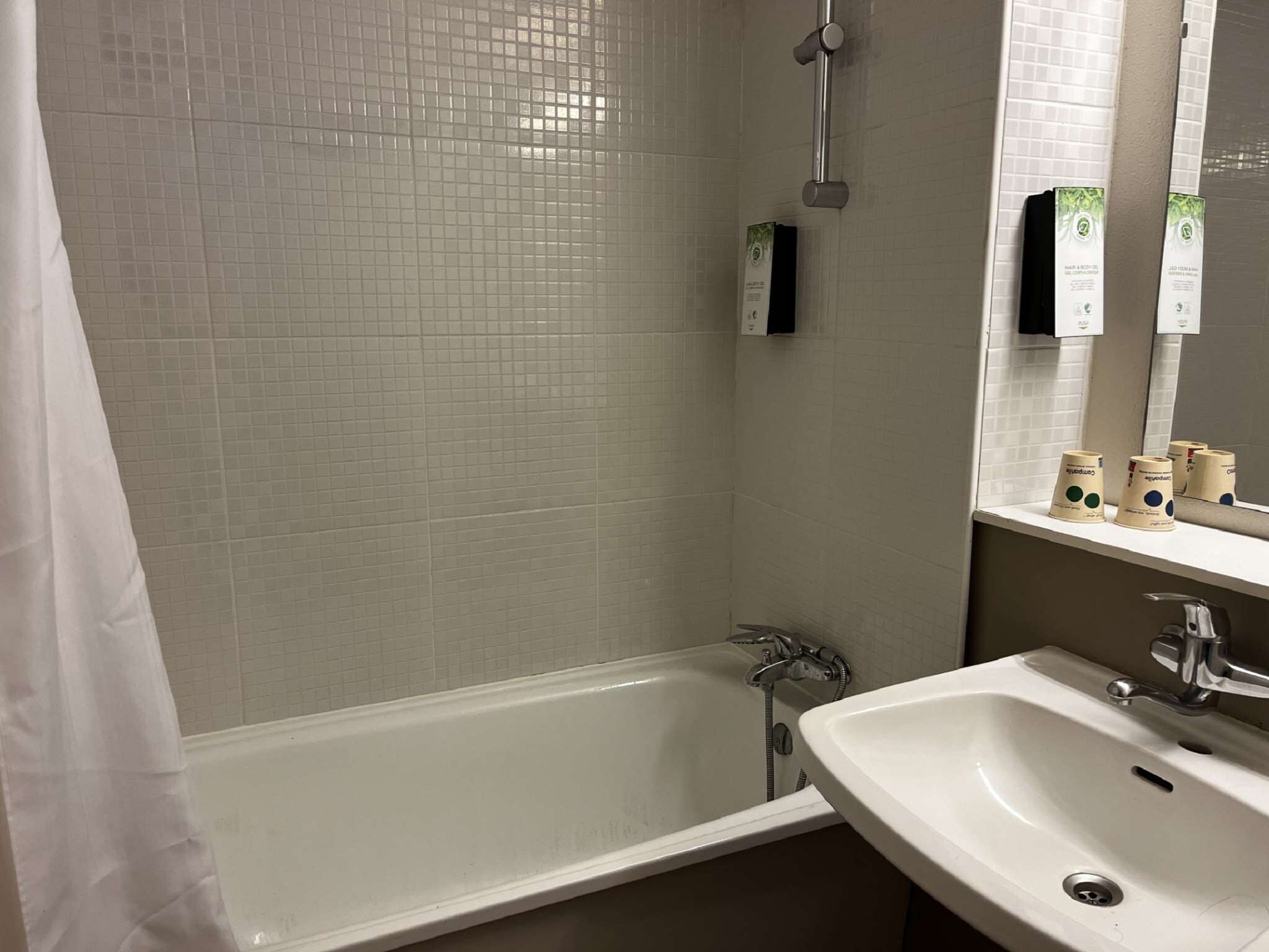 A bathroom with a bathtub, a sink, and a mirror.
