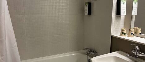 Un baño con bañera, lavamanos y espejo.
