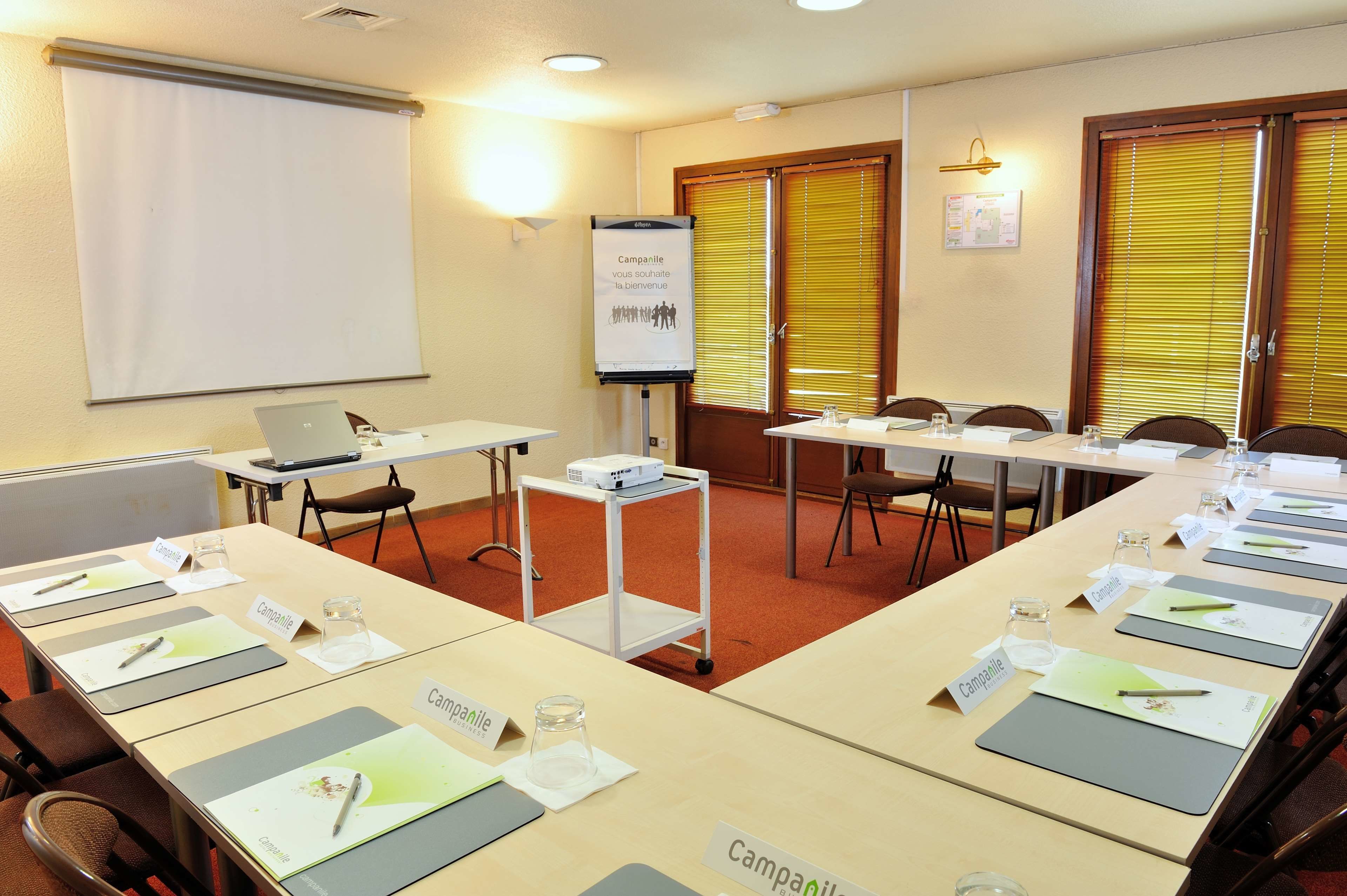 A conference room with a long table, nameplates, and a projector screen.