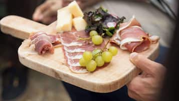 A wooden board with various food items including cured meats, cheese, grapes, and a leafy salad.