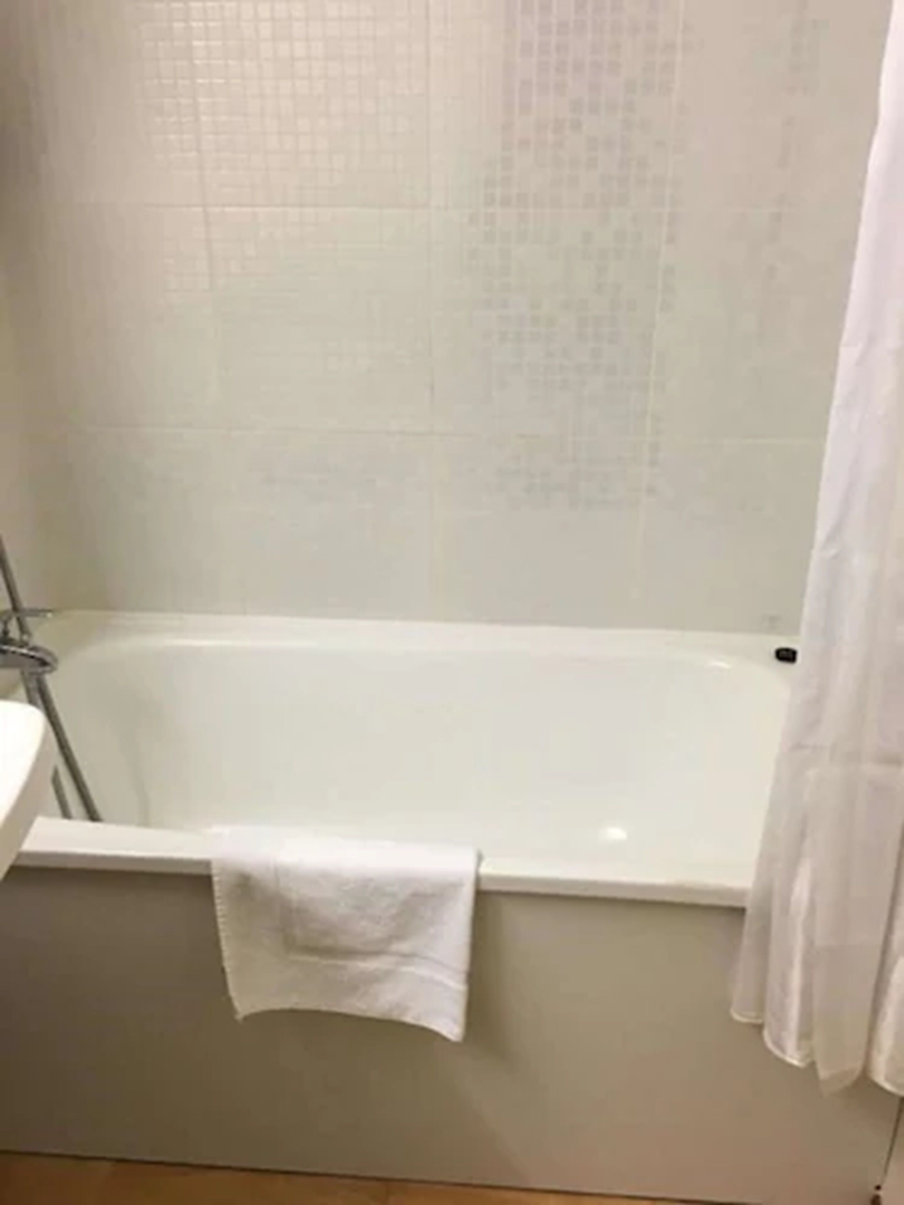 A bathroom with a bathtub, a sink, and a towel hanging on the tub.