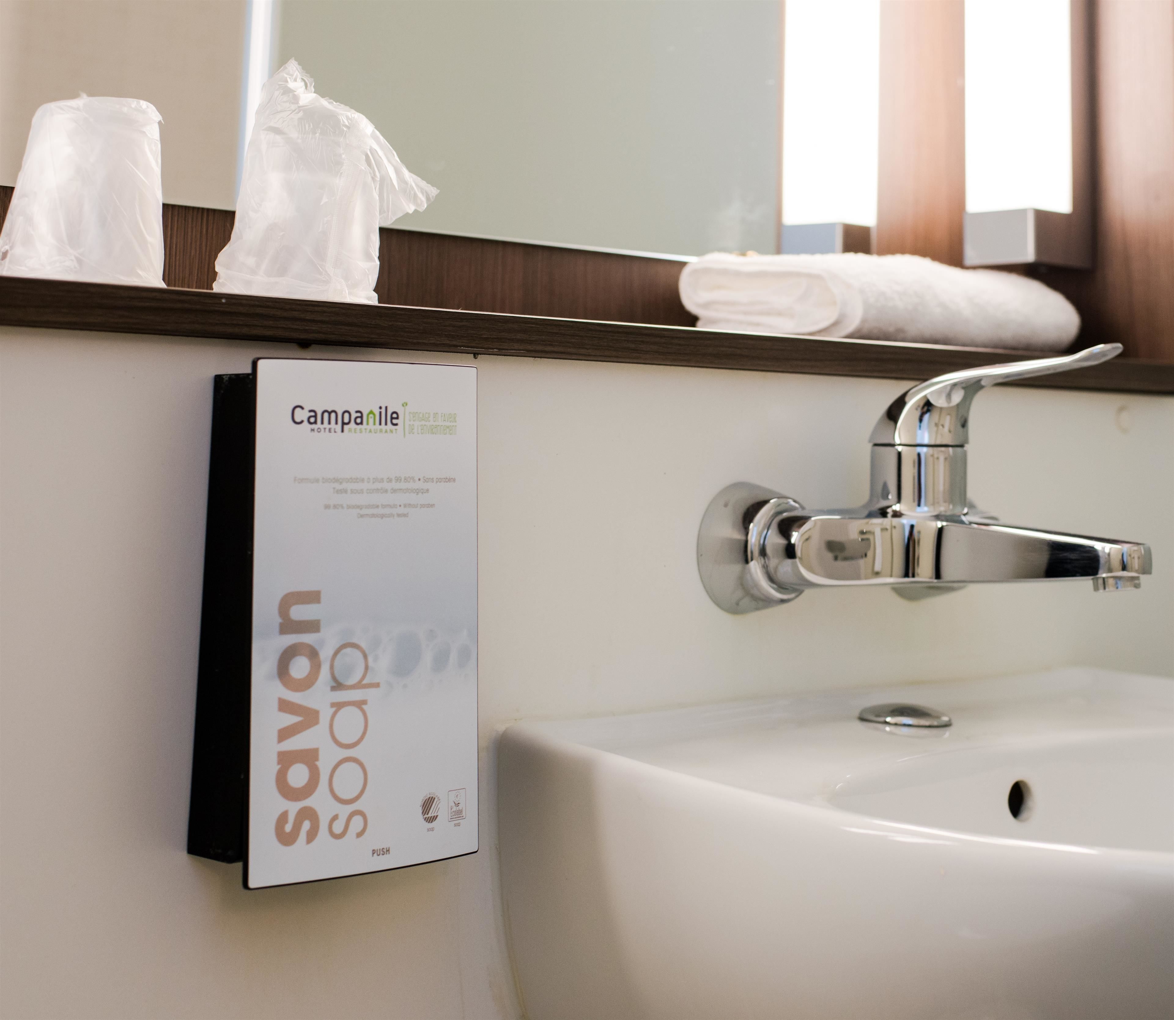 Un baño de hotel con un lavamanos blanco, un grifo cromado y un dispensador de jabón con la etiqueta 'Campanile Hotel Restaurant'.