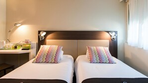 Una habitación de hotel con dos camas, un escritorio y una mesita de noche.
