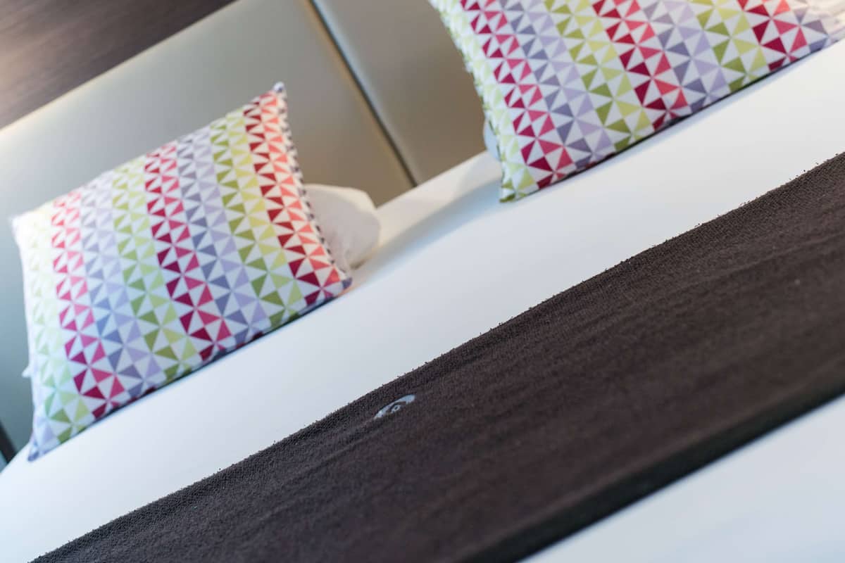 Un gros plan d’un lit avec un matelas blanc et deux oreillers ornés d’un motif géométrique coloré.