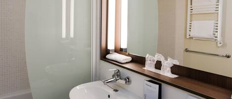 Un baño con lavamanos blanco, un espejo y un perchero para toallas.