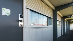 Un pasillo con una ventana, una puerta con el número y un radiador.