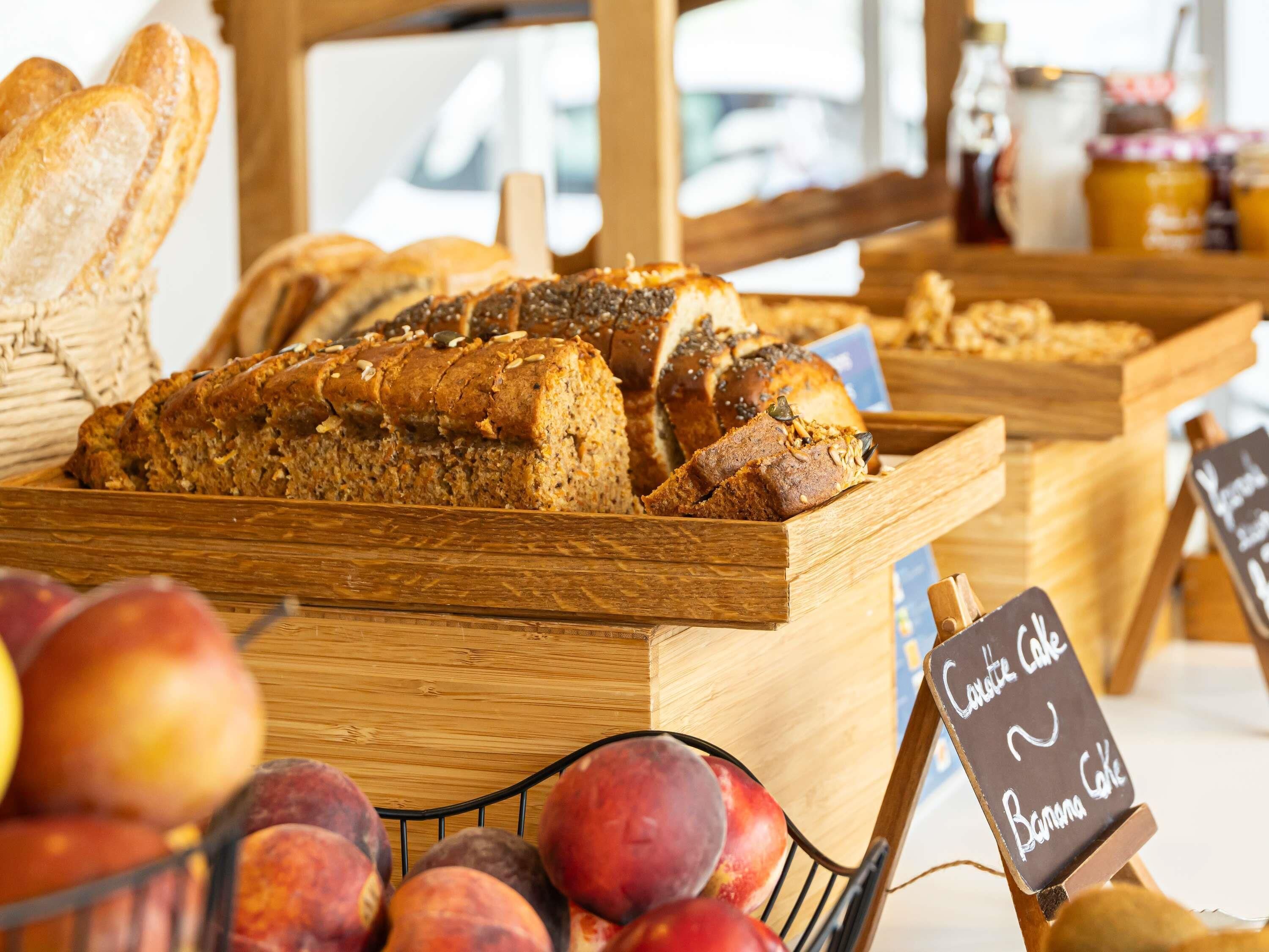 Une vitrine de boulangerie présentant différentes sortes de pains, ainsi qu’un panneau indiquant « gâteau aux carottes » et « gâteau à la banane ».
