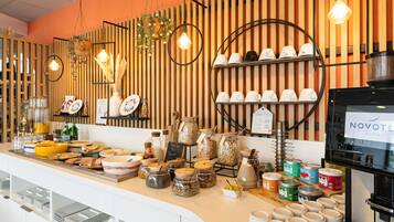 A buffet counter with various food items, jars of condiments, and a coffee machine.