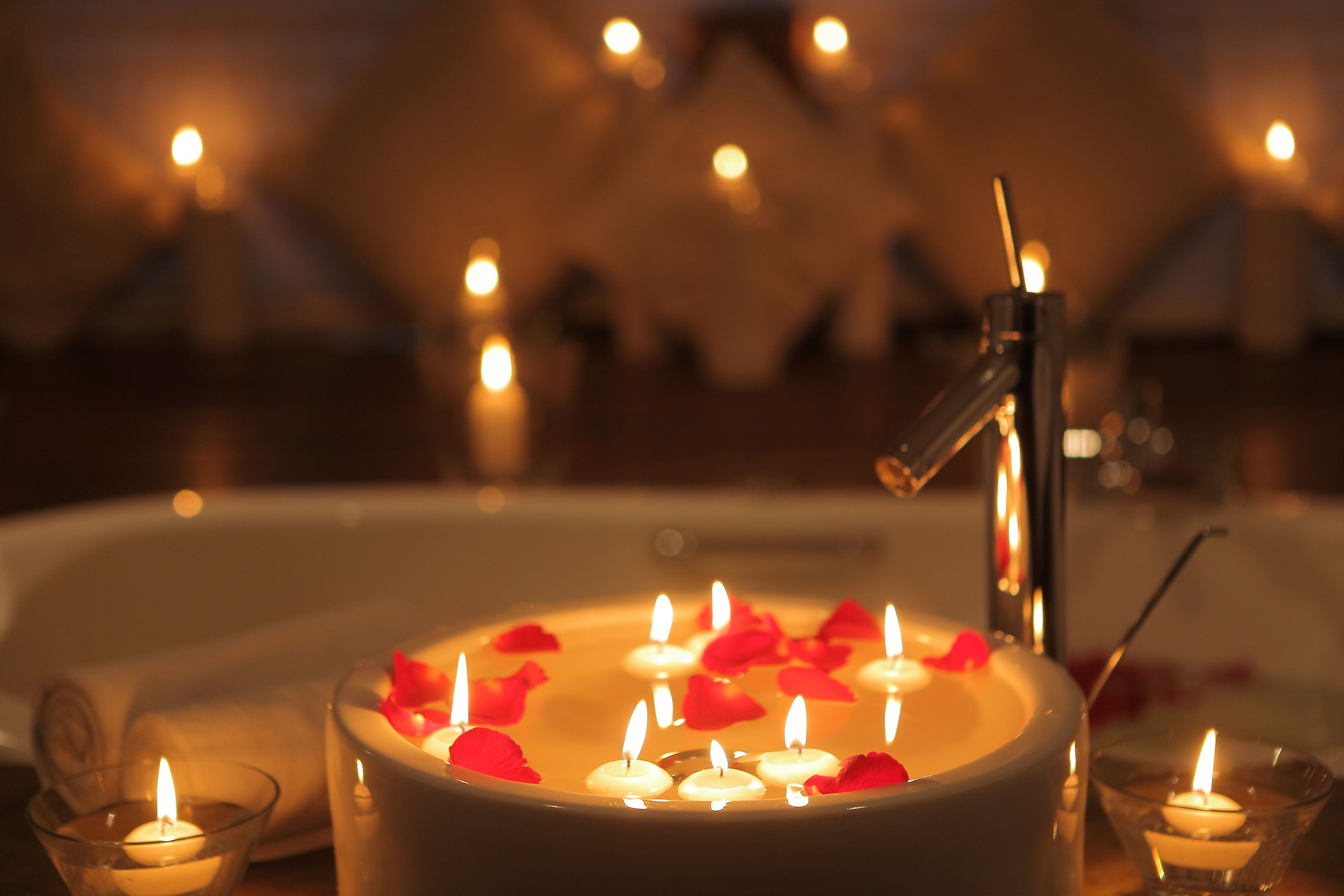 A bathtub with candles and rose petals.
