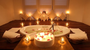 A spa room with a large bathtub surrounded by candles and rose petals. - Jetwing Beach (Negombo)