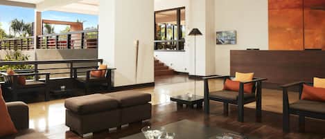 A spacious living area with a modern design, featuring a sofa set, a coffee table, and a bookshelf.