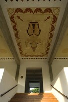Una escalera con mural decorativo en el techo y barandillas de madera.