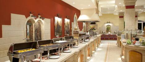 A buffet setup with multiple serving stations, a central decorative area, and a tiled floor.